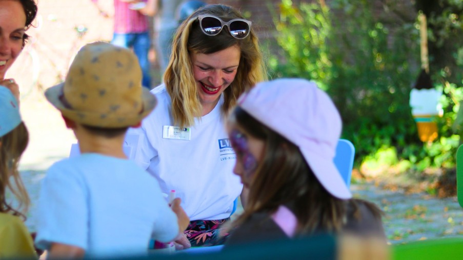 Das Bild zeigt zwei Kinder und zwei Erwachsene beim gemeinsamen Malen.