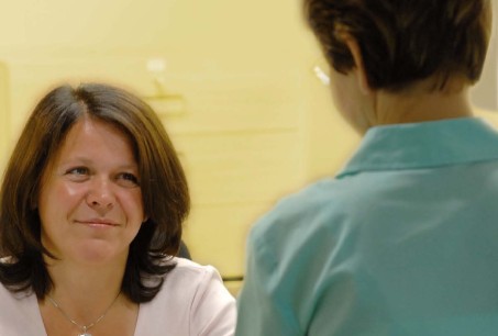 Foto: Arzthelferin im Gespräch mit einer Patientin.