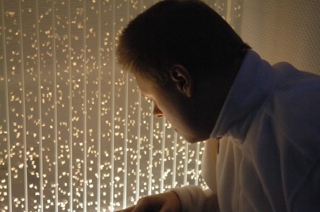 Foto: Mann schaut aus dem Fenster und betrachtet Leuchtvorhang